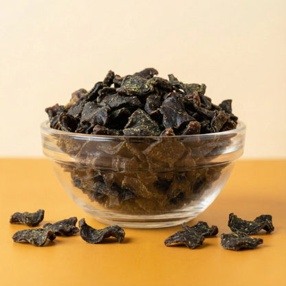 Clear glass bowl filled with Oscar Daisy dog treats on a beige background