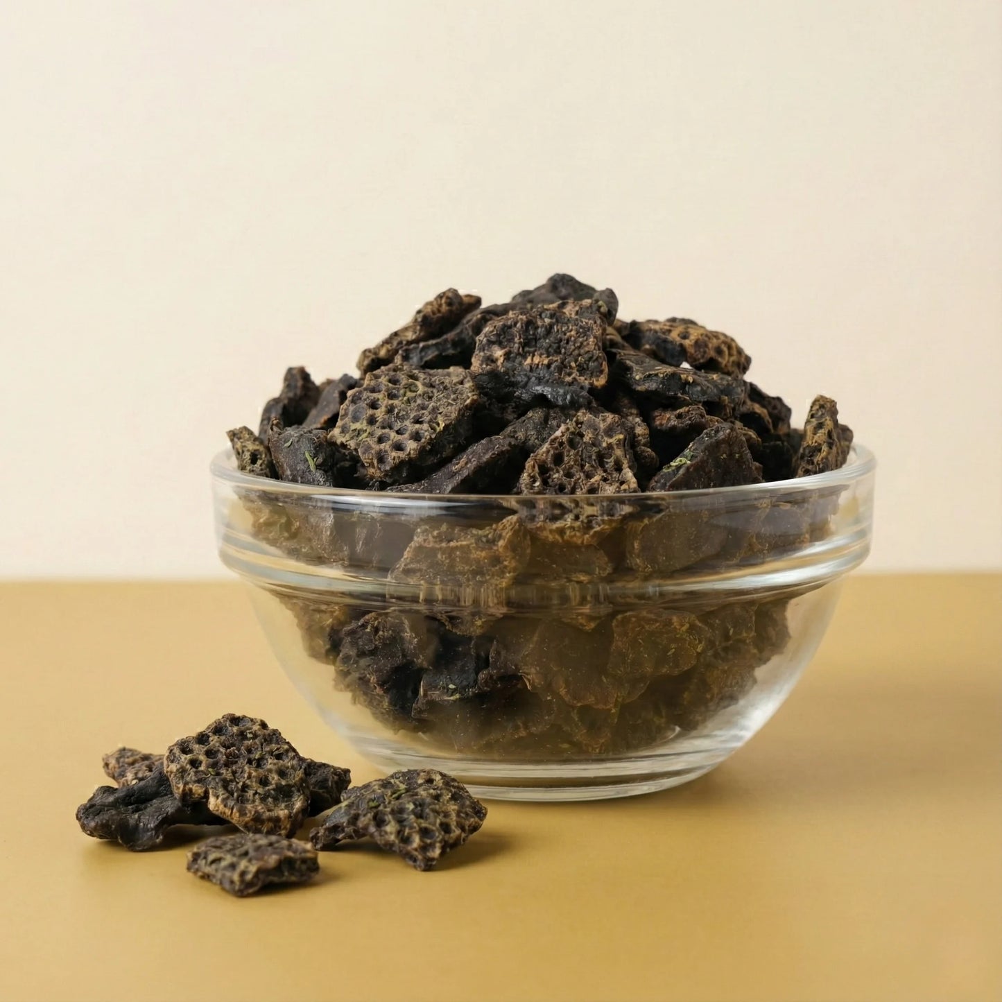 Glass bowl filled with dark brown healthy dog treats on a beige background