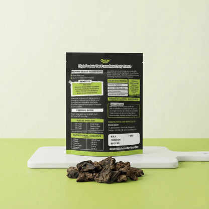 Back side of Oscar Daisy Liver Pirandai dog treats pouch showing ingredients, feeding guide and nutrition information with treats on white board and green background